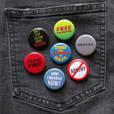 A bunch of round colorful anti-genocide pinback buttons pinned to a black denim pocket, phrases include: Free Palestine, Grieving, End The Genocide in Gaza, Dont Stop Talking About Palestine, Ceasefire!, Arms Embargo Now! & No Apathy.