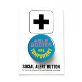 A round teal blue pinback button that reads ABLE BODIES ARE TEMPORARY in a neon red-pink & neon yellow text. Button is on a white Social Alert Button backing card with a black plus sign at the top.
