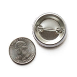 Back of a metal pinback button next to a quarter coin.
