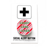 Round pinback button that says CANDY CANE LICKER in light green text on a red candy cane striped background. Button is on a Social Alert Button backing card.
