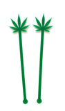 Two tall  1/8" inch thick laser cut green acrylic drink stirrers with the shape of a pot leaf cut out on top and little circles at the bottom.