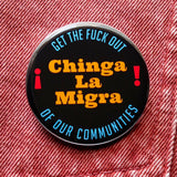 A round black pinback button that reads CHINGA LA MIGRA in goldenrod text And Get The Fuck Out, Of Our Communities in blue text rounded at the top and bottom of the button.  Badge is pinned to orange denim.