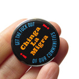 A round black pinback button that reads CHINGA LA MIGRA in goldenrod text And Get The Fuck Out, Of Our Communities in blue text rounded at the top and bottom of the button. Badge held in a hand.
