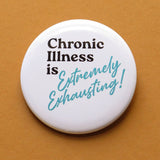 A round white pinback button that reads CHRONIC ILLNESS IS EXTREMELY EXHAUSTING in aqua & black text, that are retro 80's fonts. Button is on a Carmel colored backdrop.