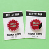A button set on perforated edge card on minty green background. Left pin reads COOKIE BAKER in mint green in shape of holiday cookie. Right pin reads COOKIE EATER in mint green, with a bite missing and cookie crumbs.