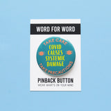 A round scrubs green pinback button that reads COVID CAUSES SYSTEMIC DAMAGE in yellow text, with peach mask icons on either side & a top curve that reds TAKE CARE, a bottom curve that reads TAKE PERCAUTIONS. Button is on a Word For Word branded backing card that reads Wear What's On Your Mind