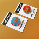 Two pinback buttons in inverse blue, orange and yellow colors that reads DOUBLE TROUBLE, each on a Perfect Pair backing card that perforates and tears down the middle to split the buttons, Keep One, Share One.