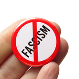 FASCISM in black text with a red circle and slash around it, to indicate being against FASCISM. Button is held in a hand.
