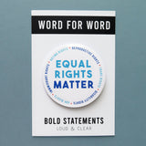 Big 3 inch round white pinback button with light blue & dark blue text that reads: TEQUAL RIGHTS MATTER. Smaller blue text runs in a circle around the permitter that says Reproductive Rights, Trans Rights, Disability Rights, Immigrant Rights, Voting Rights Button is on a Bold Statements Loud & Clear backing card.