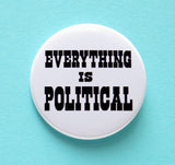 A round white 2.25" pinback button of medium size that reads EVERYTHING IS POLITICAL in chunky black text. Button is on an minty aqua background