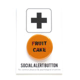 Round caramel colored pinback button that reads FRUIT CAKE in a red green swirl. Button is on a Social Alert Button backing card.