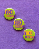 Three round 1.25" pinback buttons with a lime green grid pattern background that read FUCK EUGENICS in golden yellow text with purple rectangles behind. Badges are pinned to a dark lavender cotton fabric in a diagonal line.