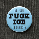 A round light blue pinback button that reads FUCK ICE in thick black text, and GET OUT OF OUR CITY in thinner black text, above & below.  pinned to black denim