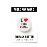 Round white pinback button that reads I LOVE USED BOOKS in 3 lines, with "love" being represented by a red heart illustration. Button is on a WORD FOR WORD branded backing card, What We Really Love.