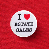 A round white pinback button that reads I LOVE ESTAET SALES with love being a red heart. Button is pinned to a red sweatshirt