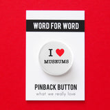 A round white pinback button that reads I LOVE MUSEUMS, love being represented by a red heart. Button is pinned to a Word For Word, What We Really Love branded backing card.