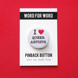 A round white pinback button that reads I LOVE QUEER ARTISTS in a black serif font, the love being indicated by a red heart. The button is on a white backing card that reads WORD FOR WORD in a black rectangle at the top, and reads Pinback Button, at the bottom of the card.