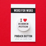 A round white pinback button that reads I LOVE SCIENCE with love being indicated by a red heart. Button is on a branded backing card.