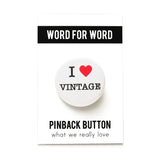 A round white pinback button that reads I LOVE VINTAGE. Love represented by a red heart. Button is on a Word for Word Pinback Button branded card, What We Really Love