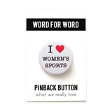 Round white pinback button that says I love women artists with a red heart. On a Word For Word backing card.