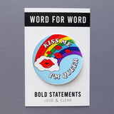 Big 3 inch round light blue pinback button with vintage Lisa Frank 80's look of a rainbow with a cloud, and red pouty lips, with text that reads: KISS ME, I'M QUEER. Button is on a Bold Statements Loud & Clear backing card.