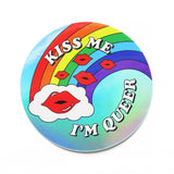 A round retro vibe holographic sticker with a rainbow that ends in a cloud with glossy red lips, and little satellite lips, that reads KISS ME, I'M QUEER