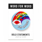 Big 3 inch round light blue pinback button with vintage Lisa Frank 80's look of a rainbow with a cloud, and red pouty lips, with text that reads: KISS ME, I'M QUEER. Button is on a Bold Statements Loud & Clear backing card.