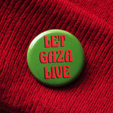 A round olive green pinback button that reads LET GAZA LIVE in a red art nouveau font. The button is pinned onto a red knit hat.