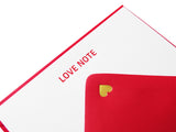A white note card with LOVE NOTE embossed in red gloss type at the top, with a red envelope, with a tiny gold heart at the close of the triangle.