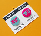 Two pinback buttons on a backing card with a center perforation to tear & share with a friend. Button on the left reads NOT SISTE with a teal background and magenta pink text. Right sided button reads NOT SISTERS in lteal with a magenta pink background.