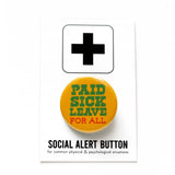 a round marigold yellow-orange pinback button that reads PAID SICK LEAVE in green text, and FOR ALL in red text. Button is pinned to a Social alert Button backing card.