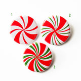Three round pinback buttons that look like holiday red, white & green peppermint candies. A number is next to each peppermint, 1, 2, 3