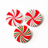 Three round pinback buttons that look like holiday red, white & green peppermint candies