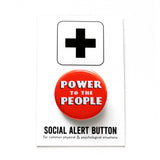 Round red-orange pinback button with white art deco text that reads POWER TO THE PEOPLE with a black drop shadow. Button is on a Social Alert Button backing card.