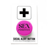 Round medium pink pinback button that reads SEX POSITIVE in black text, two lines.  Pinback button is on a Word for Word branded Social Alert Button Backing Card.