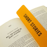 A rich marigold yellow  vertical bookmark that reads SHORT STORIES in gunmetal silver foil embossed text, marking the start of the 1967 Raymond Carver short story, Will you please be quiet, please?