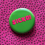 Round rich green pinback button reads SICKO! in hot pink text. Pinned to a vintage pink shirt with teeny tiny triangles