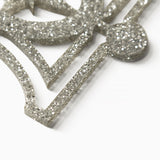 Close up of a silver glitter holiday ornament showing the 1/8" thickness of the ornament, the glitter & precise clean cut out.