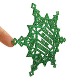 A side view of a green glitter acrylic holiday ornament, showing the eighth inch thickness of the large rather flat holiday ornament for hanging on a tree or wall.