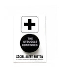 Round black pinback button that reads THE STRUGGLE CONTINUES in white text. Button is on a Social Alert Button backing card.