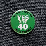 A round green 1.25" pinback button that reads YES ON PROP 40: One time 5% Wealth Tax, Only On Billionaires,  in white text. Button is pinned to black denim.
