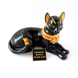 Rectangle enamel pin that says FEMINIST WITH A TO-DO LIST next to a bejeweled cat figurine.