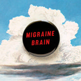 A round black pinback button that reads MIGRAINE BRAIN in red text on two lines. Button is on a vintage illustration of a fluffy cloud above mountains.