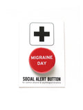 Shiny bright red pinback button with white san serif test reading, Migraine Day.  The button is attached to a white backing card with a black plus sign at the top of the card, and beneath the button it reads: Social Alert Button, for common physical & psychological situations.