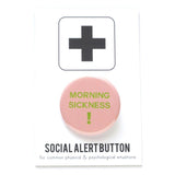 A round light pink pinback button that reads MORNIG SICKNESS ! in lime green text. Button is on a Social alert Button backing card.
