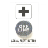 A round 1.25" pinback button on a  old tv pattern of pixelated digital noise and the text says OFF LINE in white letters/ Button is on a social alert button backing card.
