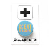 Round, visually textured light blue pinback button that reads SCENT SENSITIVE in a deep cream color with pink drop shadow. Button is on a Social Alert Button backing card.