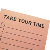Close-up of a peach check list notepad that reads TAKE YOUR TIME in black text at the top.