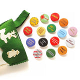 A bunch of shiny round multi-colored pinback buttons coming out of a green felt stocking: Buttons read -- Drunk Uncle, Egg Nog Fog, Star Baker, Sugar Plum Fairy, Lump of Coal, Naughty/Nice, Re-Gifter, Present Peeker, Jewish, Food Coma, Latke Lover, Gay Apparel, Nut Cracker, Fruit Cake, Candy Cane Licker and more
