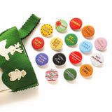 A bunch of shiny round multi-colored pinback buttons coming out of a green felt stocking: Buttons read -- Drunk Uncle, Egg Nog Fog, Star Baker, Sugar Plum Fairy, Lump of Coal, Naughty/Nice, Re-Gifter, Present Peeker, Jewish, Food Coma, Latke Lover, Gay Apparel, Nut Cracker, Fruit Cake, Candy Cane Licker and more